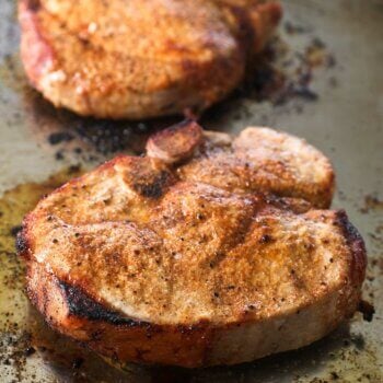 Close up angle image of broiled pork chops on a sheet pan