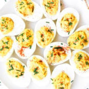 Overhead image of keto deviled eggs on a plate sprinkled with paprika and diced chives