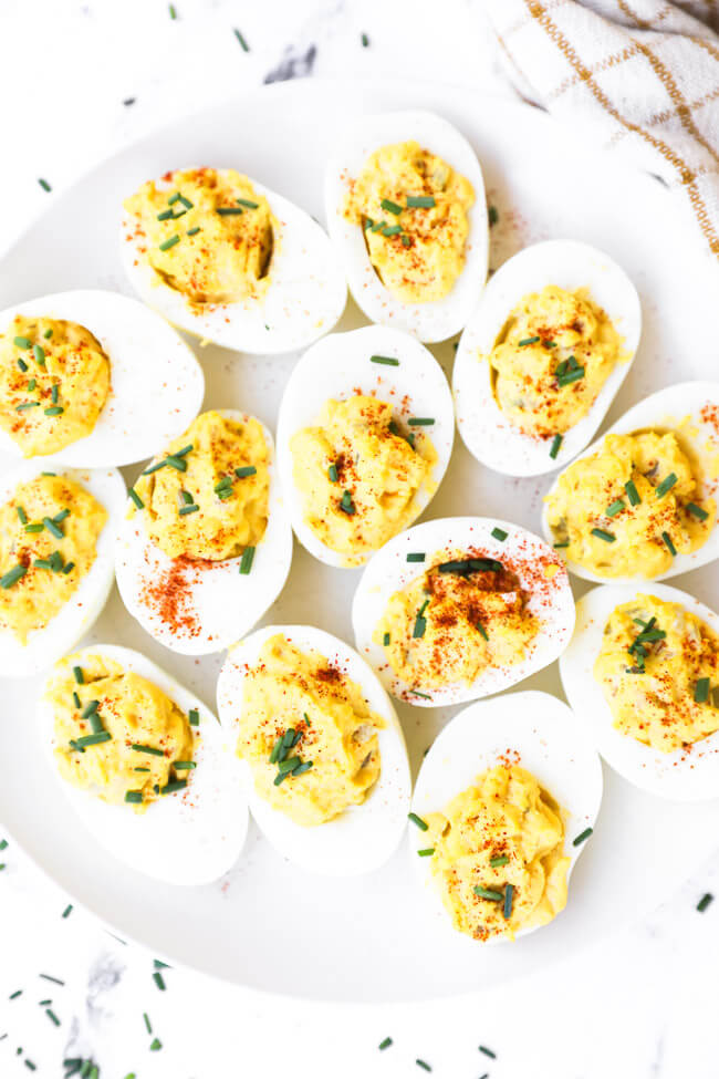 Overhead image of keto deviled eggs on a plate sprinkled with paprika and diced chives