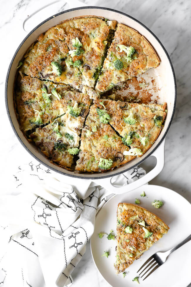 Vertical overhead image of Keto frittata in a skillet with one piece removed and served up on a plate with a fork. 