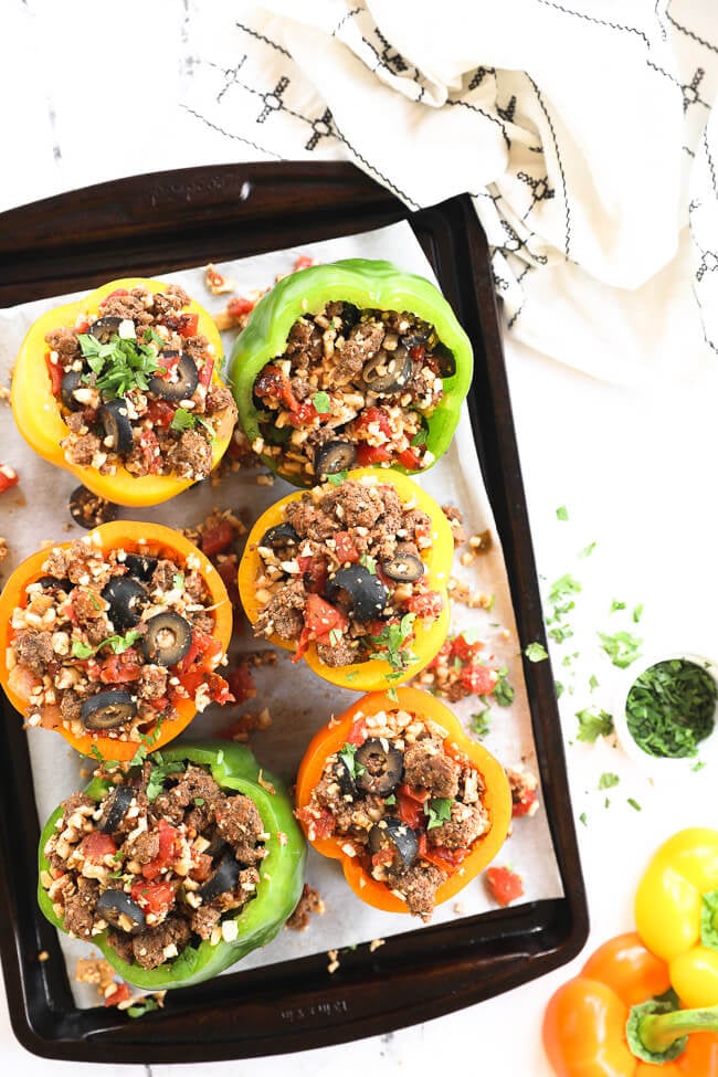 Stuffed bell peppers with ground beef and cauliflower rice on a sheet pan.