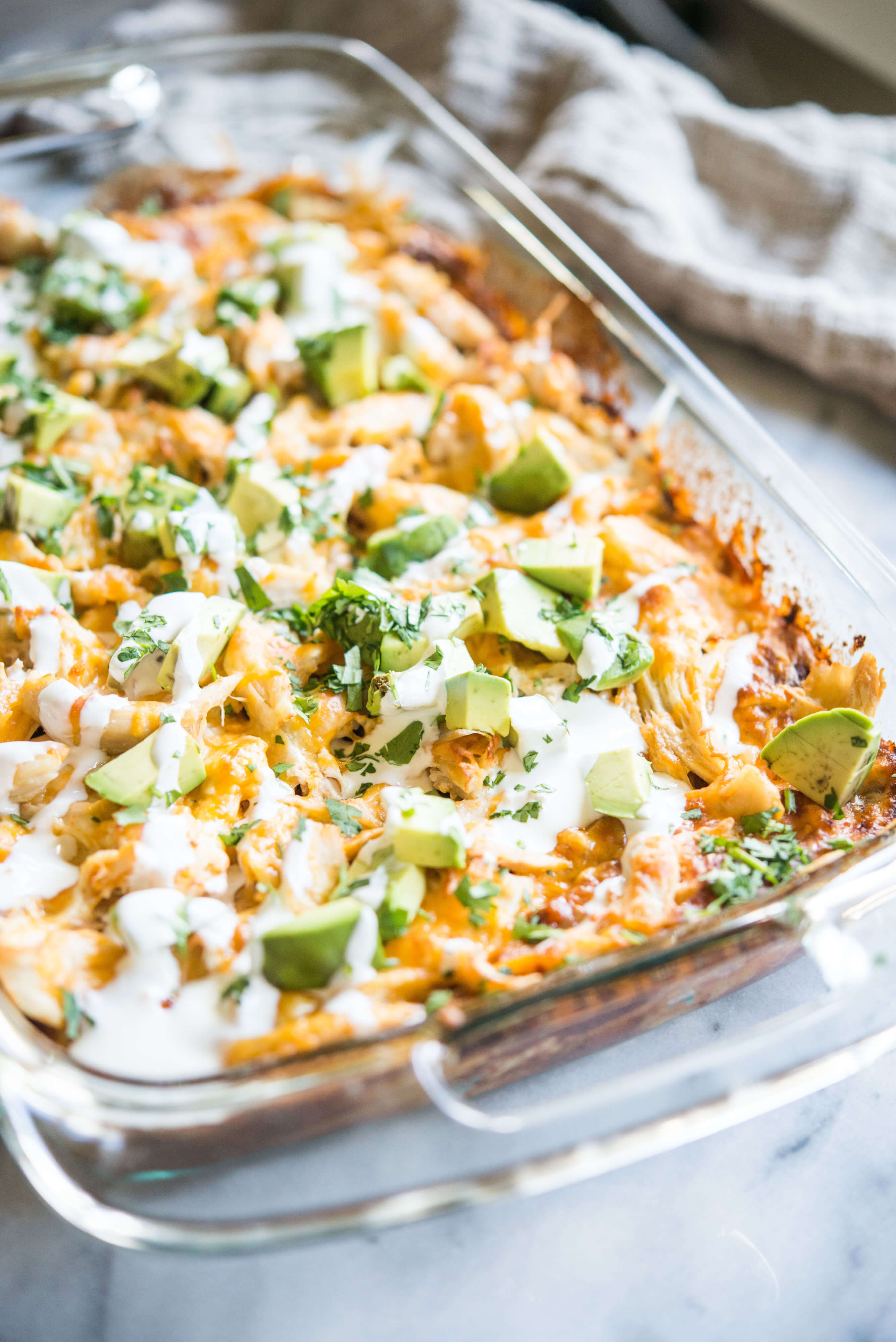 Chicken enchilada casserole with sauce and chopped avocado on top