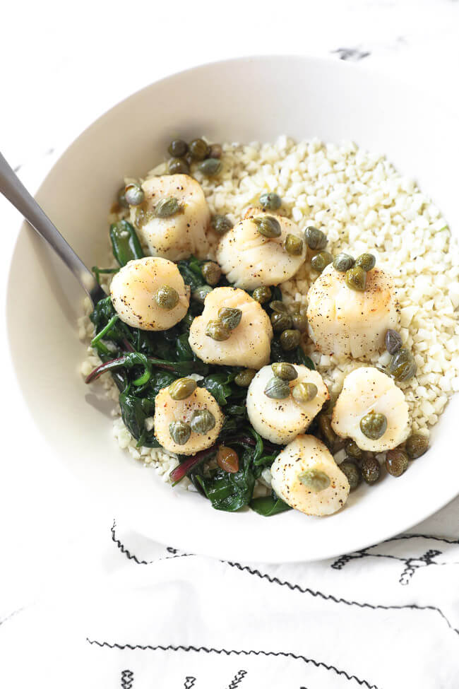 Cooked scallops in a bowl over cauliflower rice and wilted greens