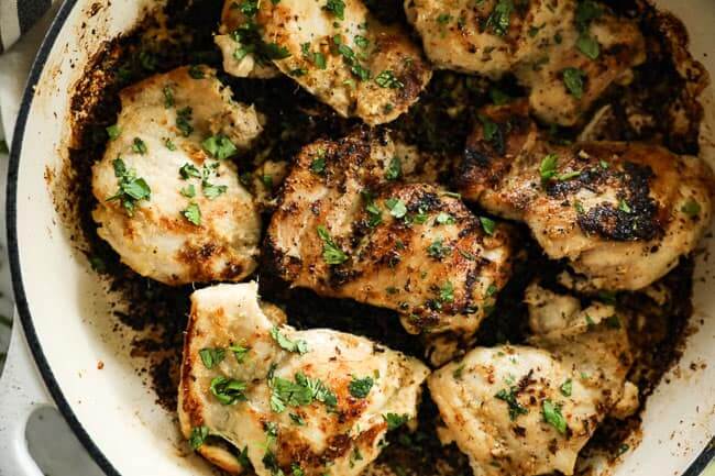 Close up image of lemongrass chicken thighs in skillet with chopped cilantro sprinkled on top. 