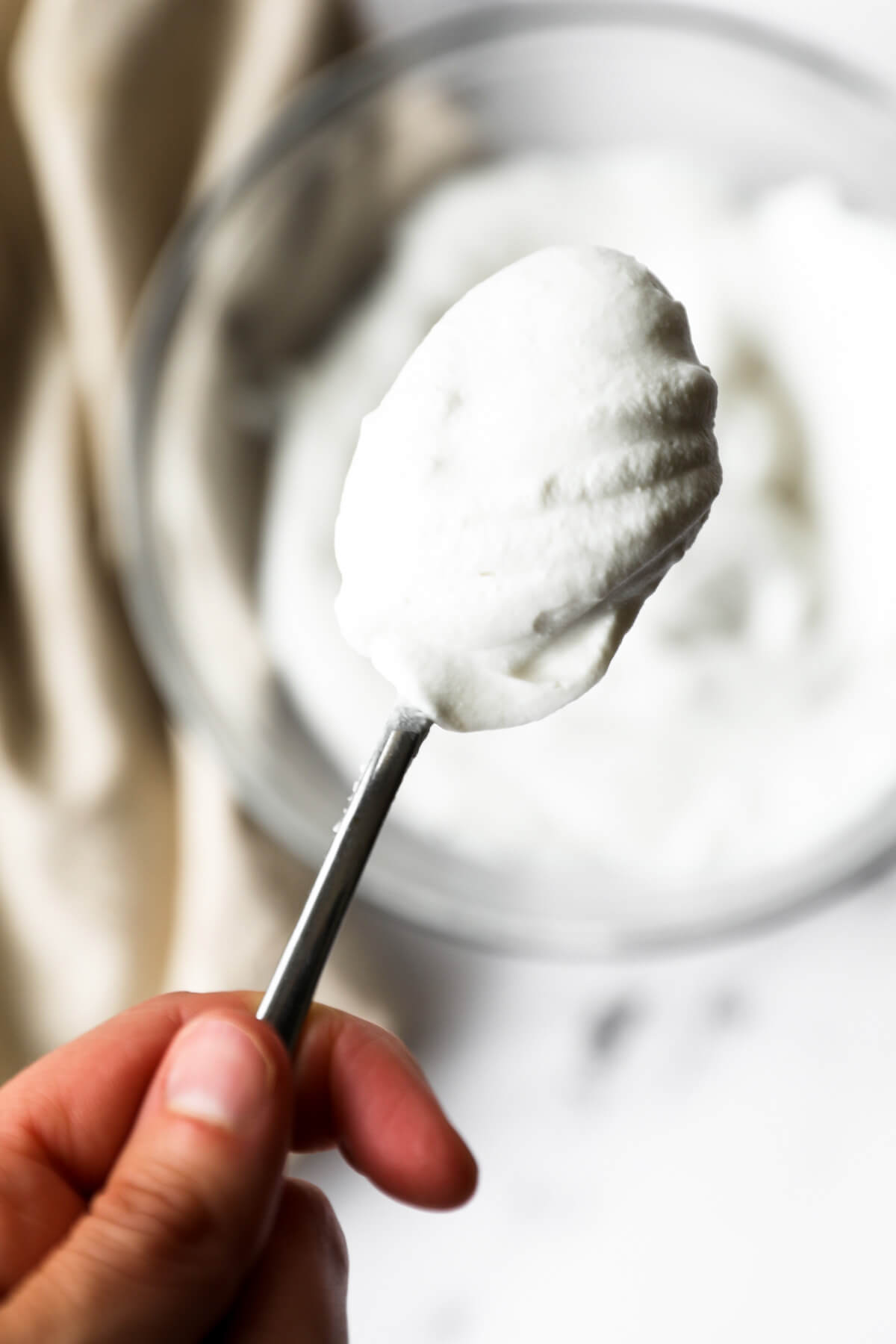 Close up image of holding a spoonful of coconut cream whipped cream. 
