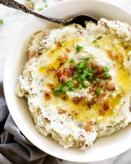 Overhead image of loaded mashed cauliflower in a bowl with bacon bits and chives