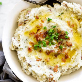 Overhead image of loaded mashed cauliflower in a bowl with bacon bits and chives