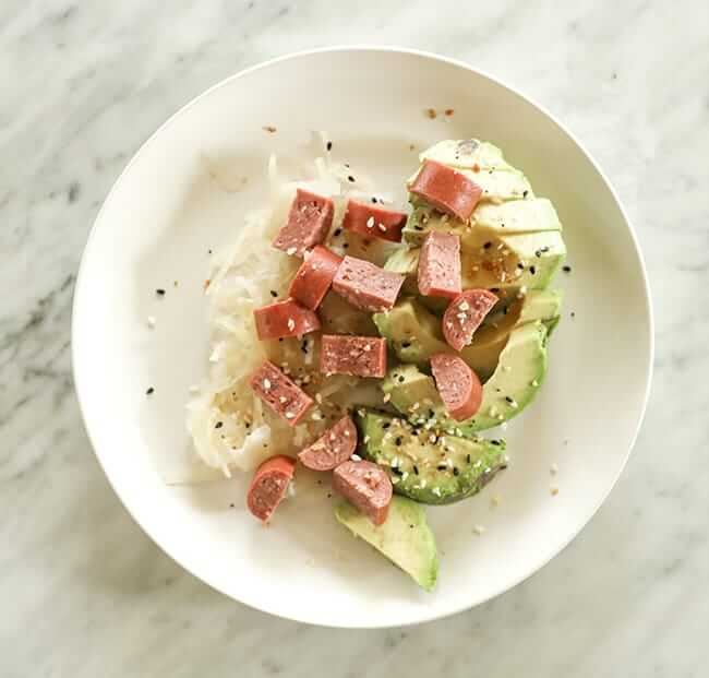 Sauerkraut, avocado and sliced hot dog on a plate