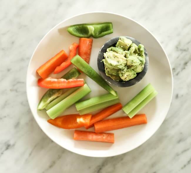 Sliced carrots and bell pepper on a plate with guacamole