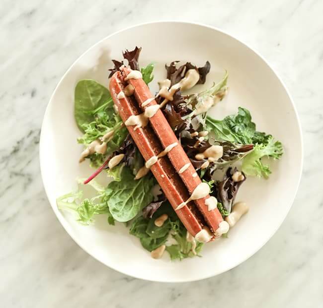 Greens with hot dot and mustard drizzle on top on a plate