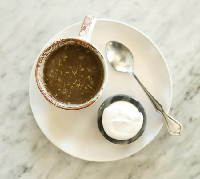 Coconut yogurt and spoon on a plate with a cup of broth