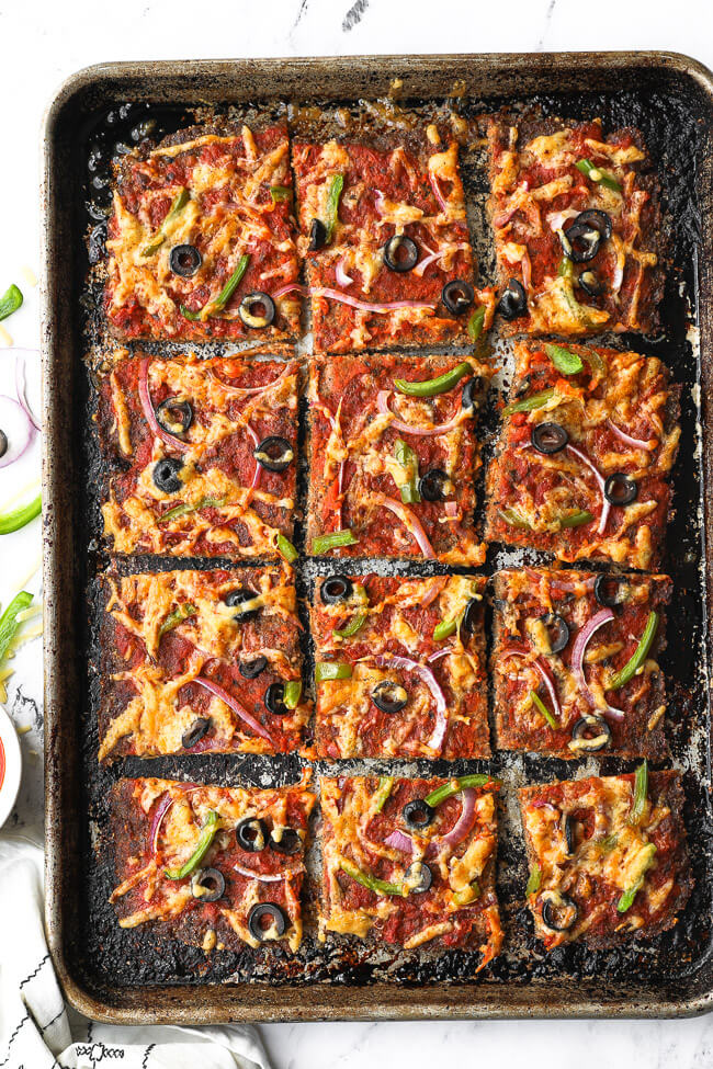 Overhead image of sheetpan with meatza cut into square slices. 