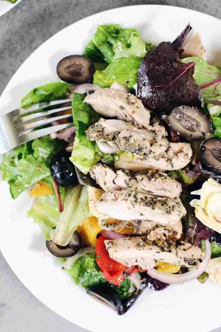 The flavors of this Paleo + Whole30 mediterranean chicken salad take it a notch above the typical salad. It's fresh, flavorful and so easy to make! Filled with fresh lettuce, chicken, olives, roasted peppers, artichoke hearts, red onion and homemade dressing. Paleo + Whole30. | realsimplegood.com