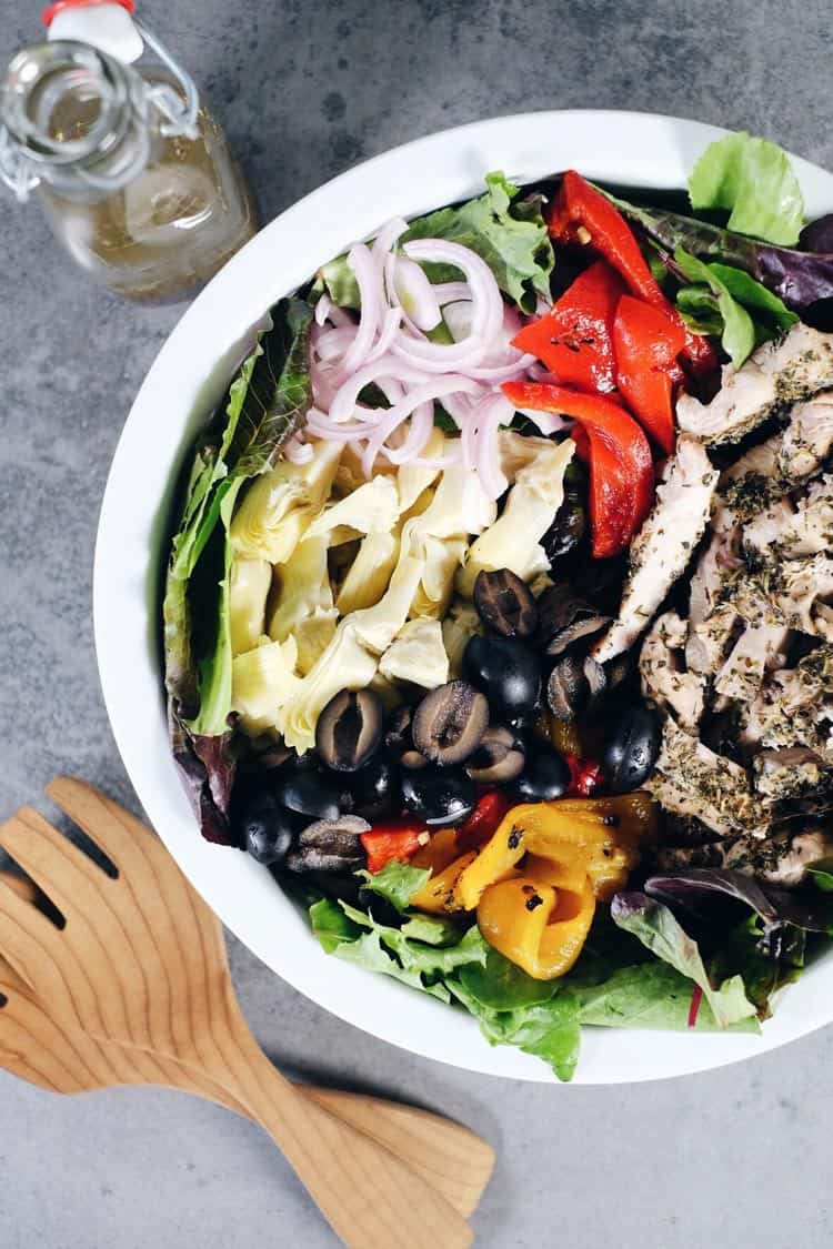 The flavors of this Paleo + Whole30 mediterranean chicken salad take it a notch above the typical salad. It's fresh, flavorful and so easy to make! Filled with fresh lettuce, chicken, olives, roasted peppers, artichoke hearts, red onion and homemade dressing. Paleo + Whole30. | realsimplegood.com