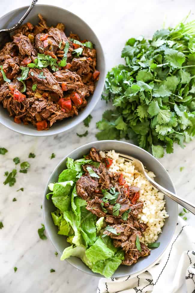 Mexican shredded beef in bowl with cauliflower rice, chopped lettuce and fork vertical photo