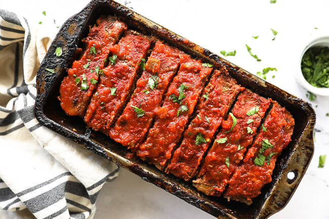 Taco meatloaf sliced in a pan with cilantro topping horizontal image