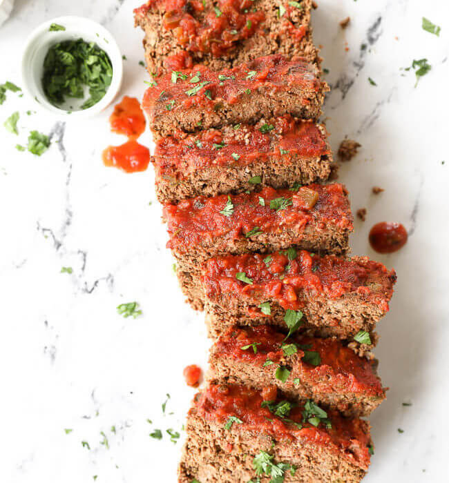 Mexican taco meatloaf sliced and laid out with cilantro and salsa topping.