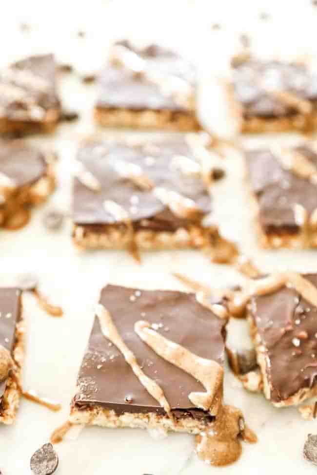 Angled shot of peanut butter bars with nut butter drizzle and sea salt on top. 