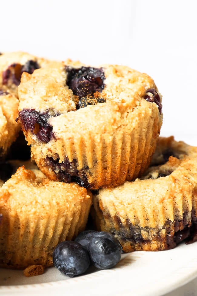 Close up straight on image of blueberry muffins stacked on a plate. 