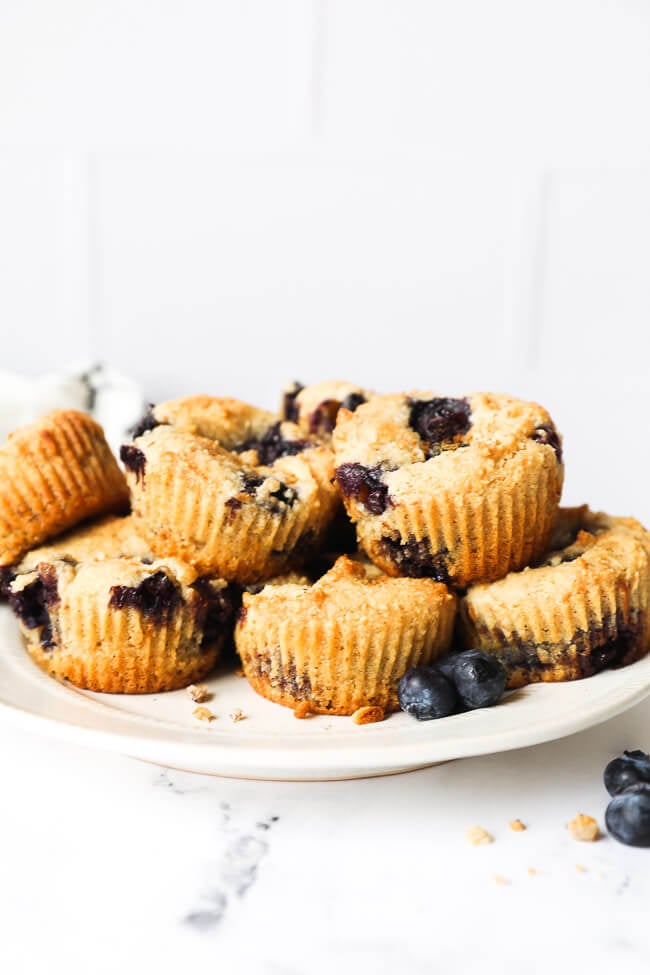 Straight on image of blueberry muffins stacked on a plate. 