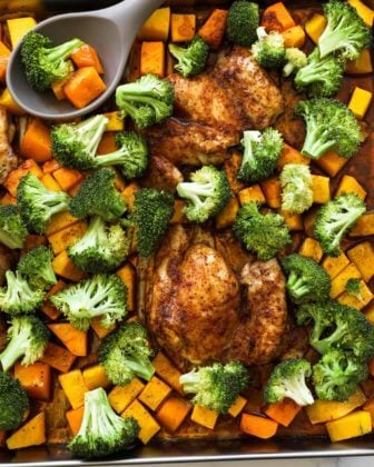 Overhead shot of one pan baked chicken and broccoli with squash pieces and a spoon in the pan