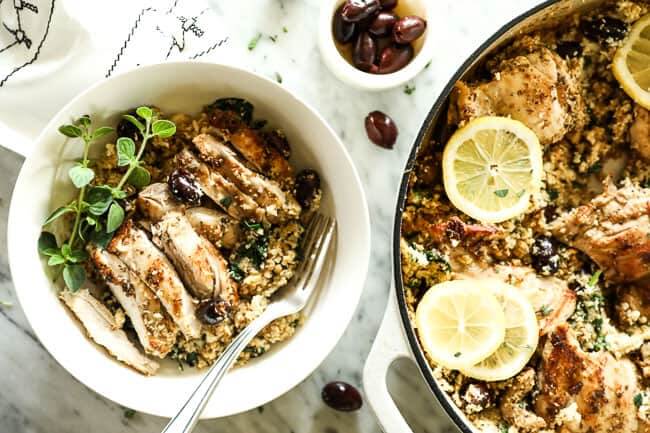 Horizontal image of one pan greek chicken dinner in skillet and served up in a bowl with a fork, with sprigs of fresh oregano on top. 