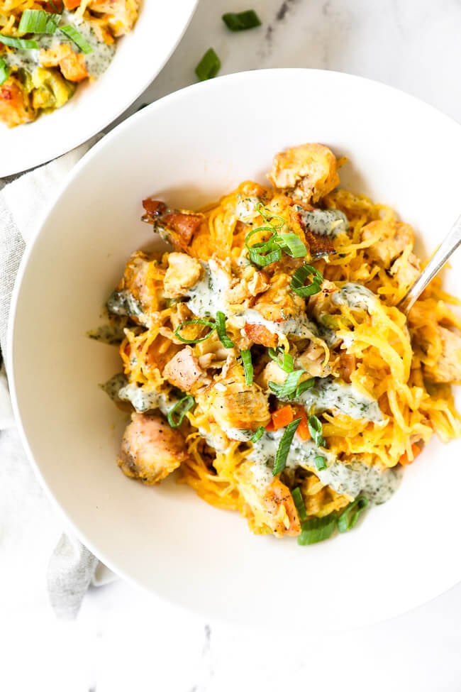 Vertical overhead close up image of buffalo chicken casserole served up in a bowl with a fork dug in. 