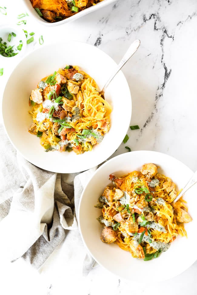 Vertical overhead image of buffalo chicken casserole served up in two bowls with forks dug in. 