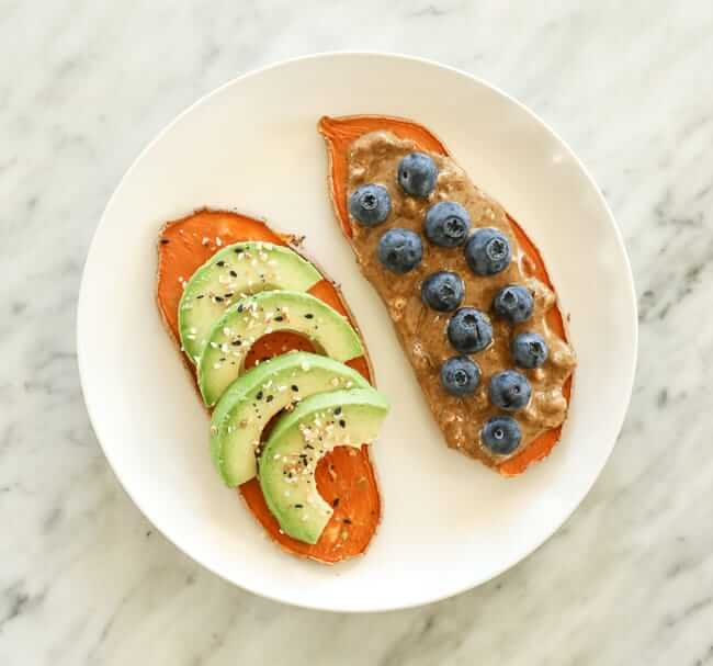 Sweet potato toast with avocado and nut butter and berry topping on a plate
