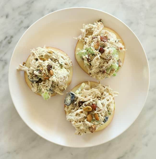 Round apple slices topped with chicken salad on a plate