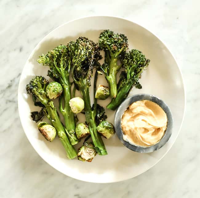 Roasted broccolini and brussels sprouts on a plate with mayo