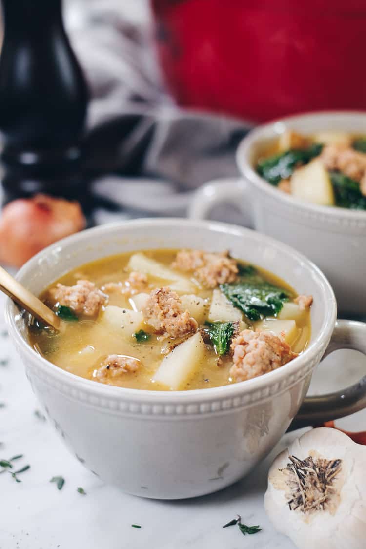 Curling up with a big bowl of this Paleo sausage soup feels so comforting and soul-satisfying. It's filled with roasted garlic, potatoes and kale. Paleo, Whole30 and Dairy-Free. | realsimplegood.com