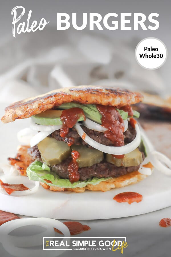 Paleo burger with plantain bun on board with avocado, onion pickle and ketchup dripping down. Close up straight on vertical image with text at top.