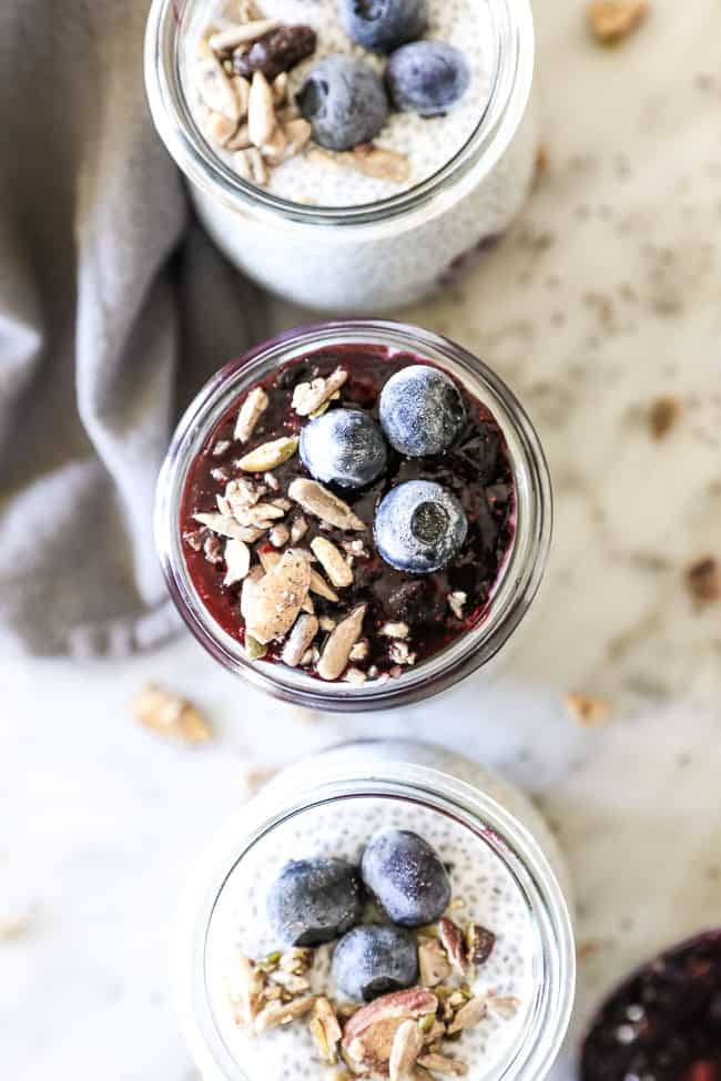 Paleo chia seed pudding overhead vertical shot of jars in line with blueberry at top
