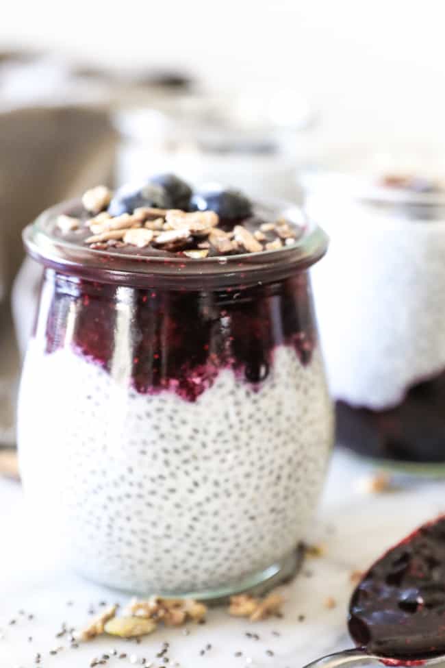 Paleo chia seed pudding straight on shot of jar on left with blueberry at top and spoon