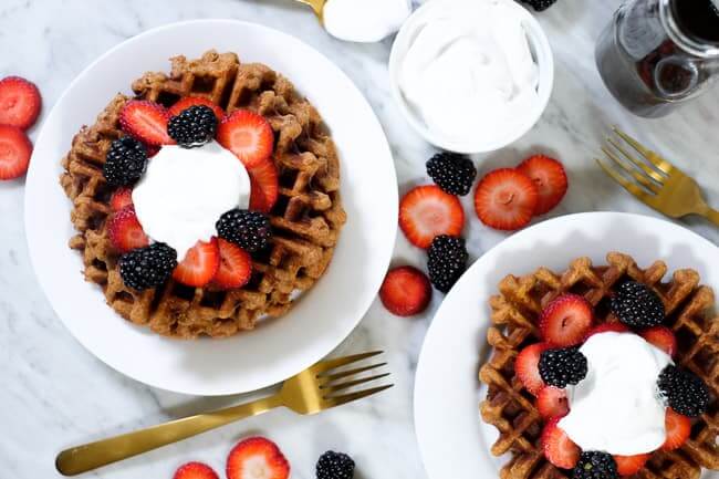 Paleo waffles topped with berries and coconut whipped cream. 