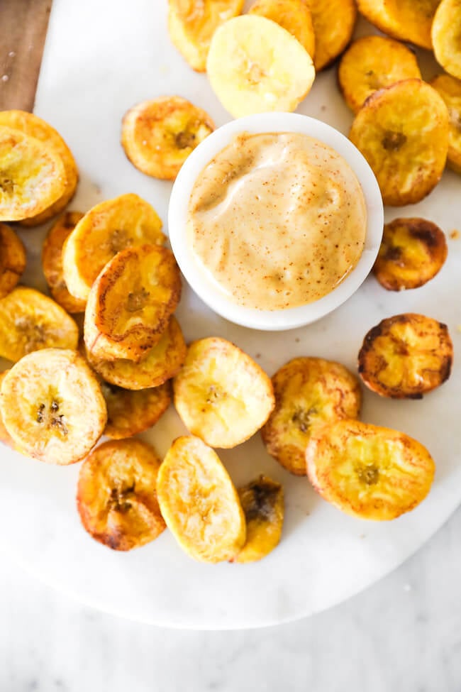 Close up vertical overhead image of pan fried plantains with dipping sauce. 