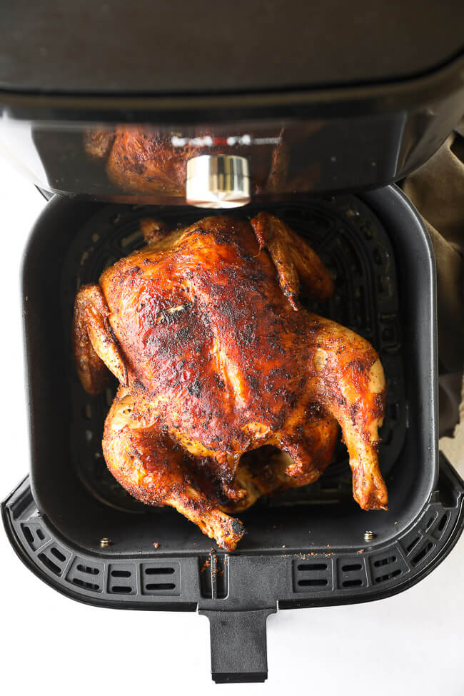 Whole roasted chicken in an air fryer basket
