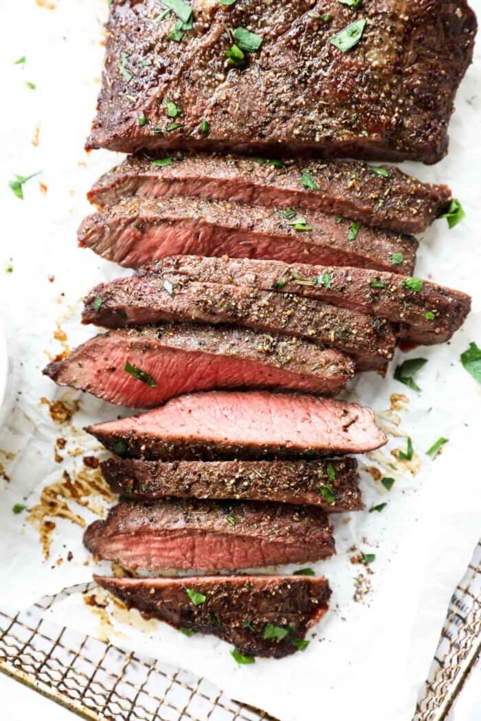 Overhead image of flank steak laid out vertically, with about half the steak sliced into thin strips.