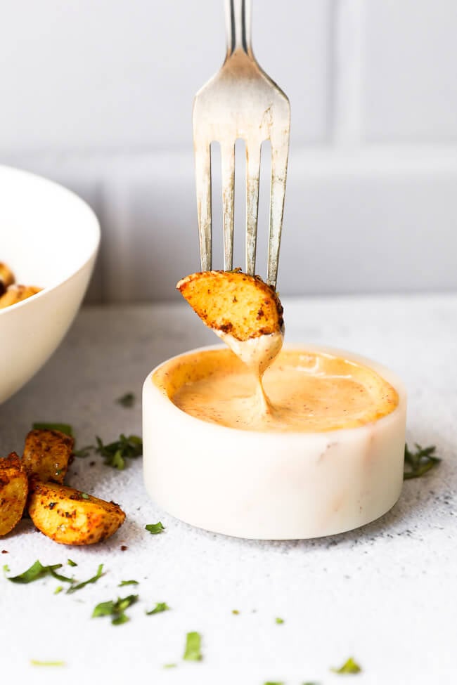 Fork with a small potato piece being dipped into an aioli sauce