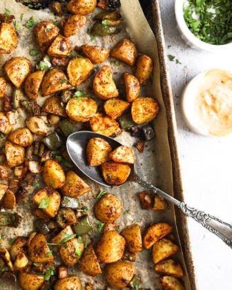Roasted mexican potatoes on a sheet pan with spoonful of potatoes