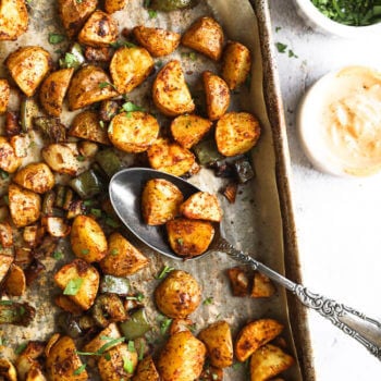 Roasted mexican potatoes on a sheet pan with spoonful of potatoes