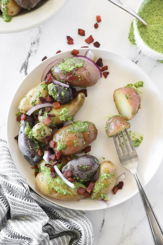 pesto potato salad on a plate with fork vertical image