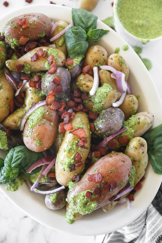 pesto potato salad in bowl with a bacon and red onion sprinkled on top close up vertical image