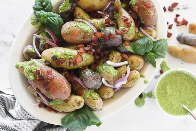 pesto potato salad in bowl with bacon sprinkled on top horizontal image