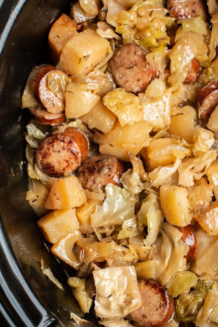 Overhead image of cabbage, potatoes and sliced sausages in slow cooker