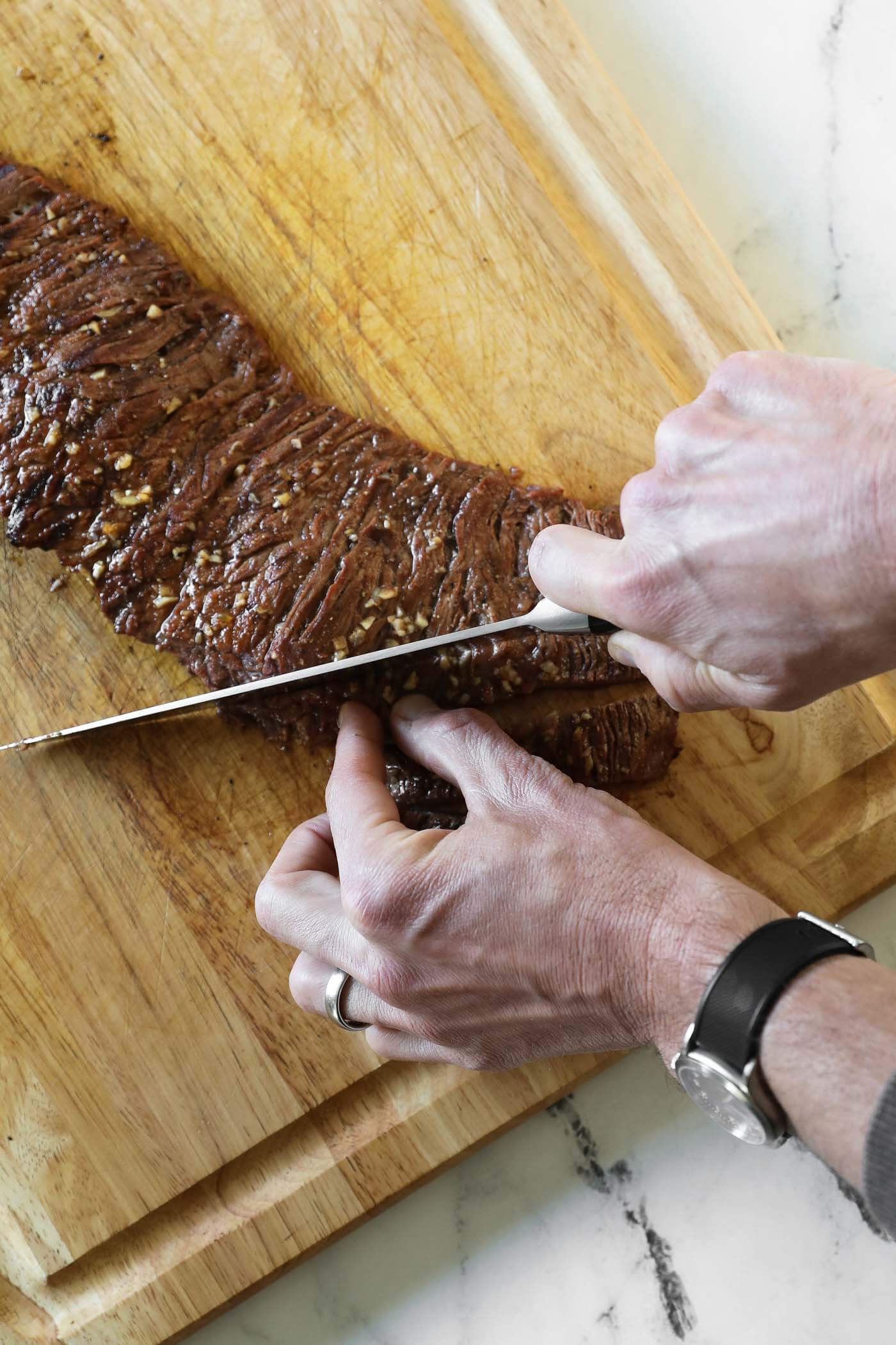 Overhead shot of hands and knife cutting carne asada