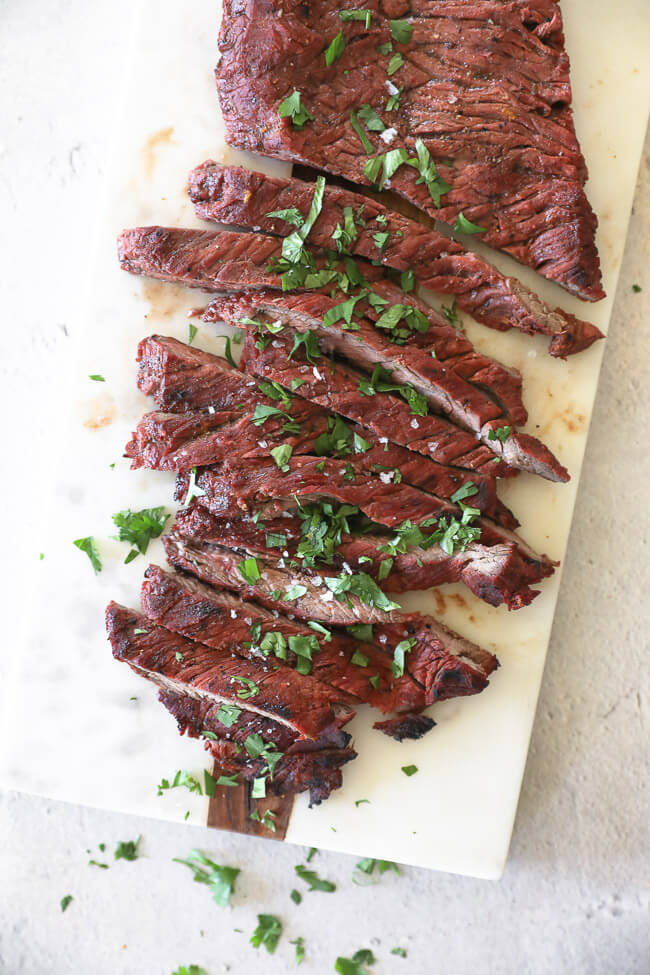 Quick and easy carne asada on a board cut into strips topped with salt and cilantro