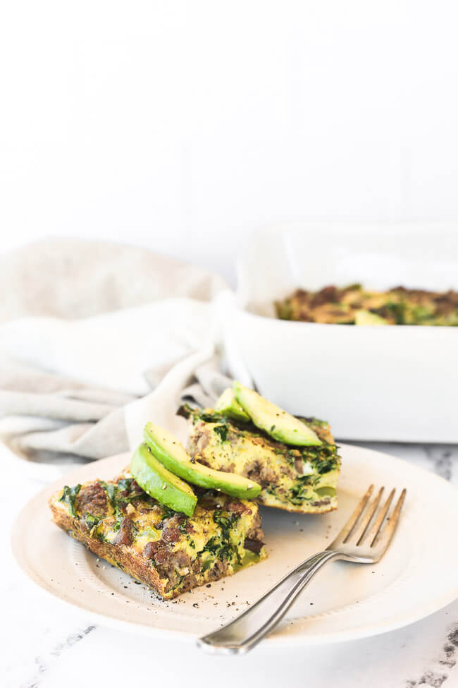 Zwei Stücke Keto-Frühstücksauflauf auf einem Teller, garniert mit Avocadoscheiben