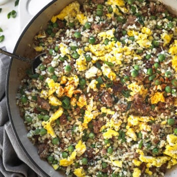 Overhead image of pan full of keto cauliflower pork fried rice with eggs, peas and green onions